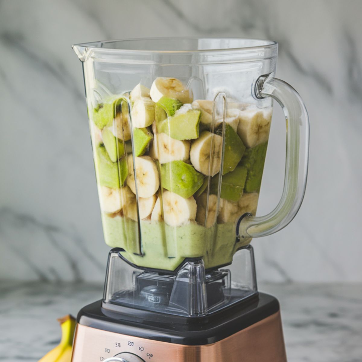 Frozen banana, yogurt, and avocado added to the spinach mixture in a blender.