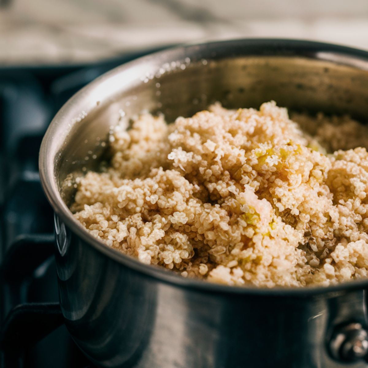 Fluffing cooked quinoa simmering inside a medium-sized saucepan.