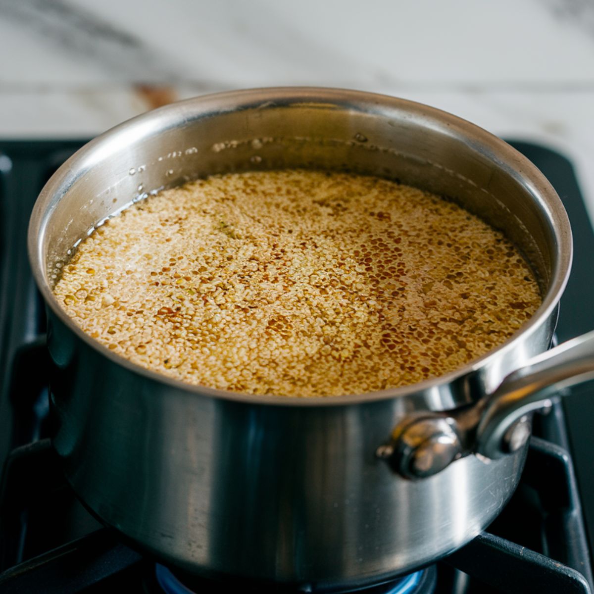 Rinsing quinoa in a fine-mesh strainer under clear running water, ready for cooking.