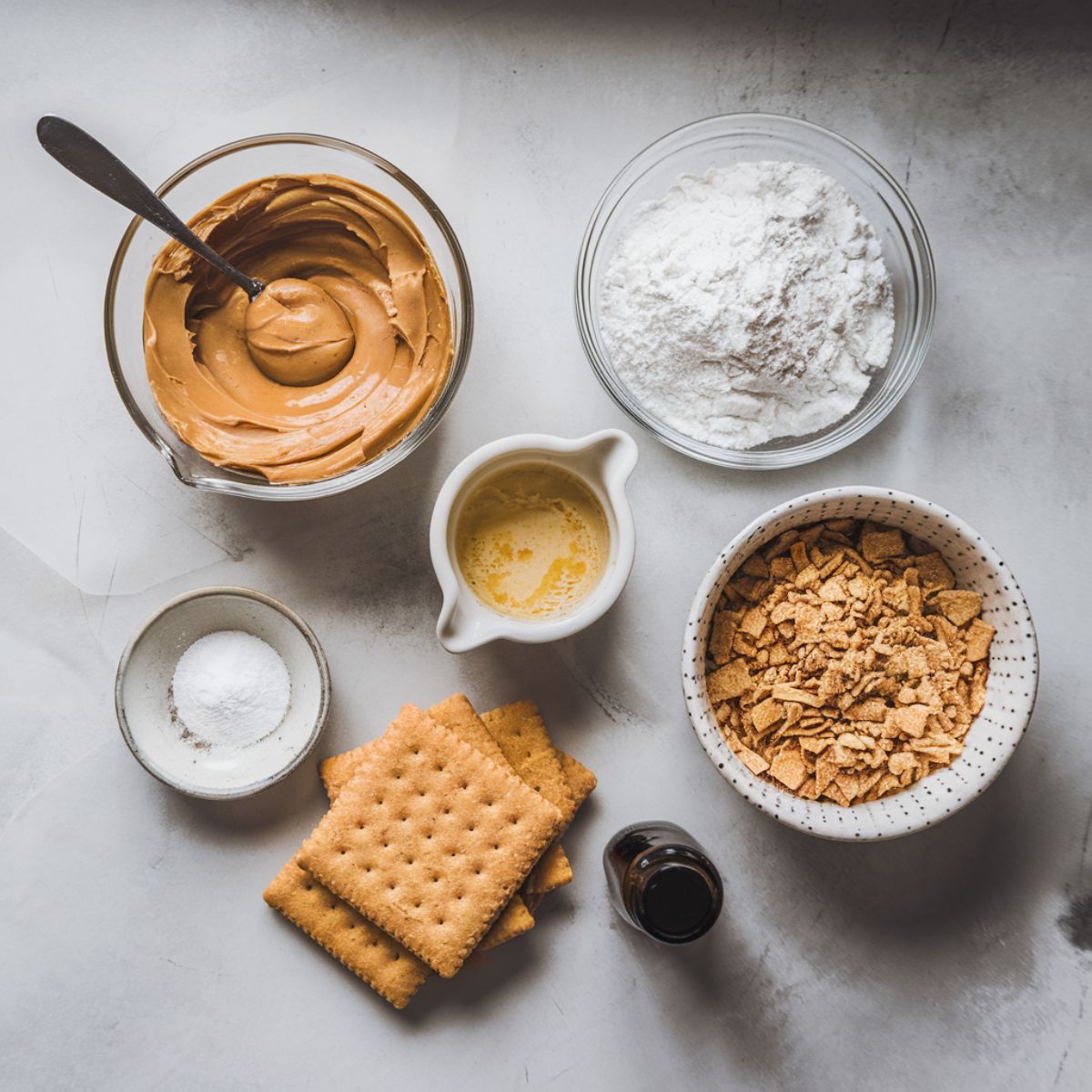 Flat lay of peanut butter bar ingredients on a clean surface, including creamy peanut butter, melted butter, powdered sugar, graham cracker crumbs, vanilla extract, and salt.