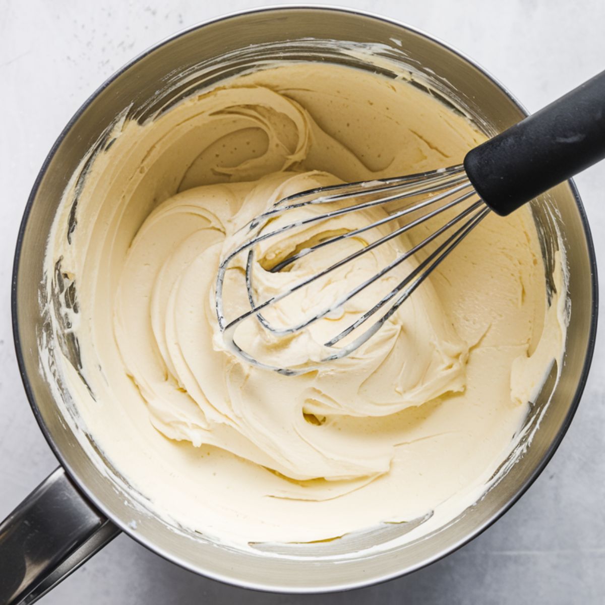 Overhead view of a mixing bowl with fluffy cream cheese frosting.