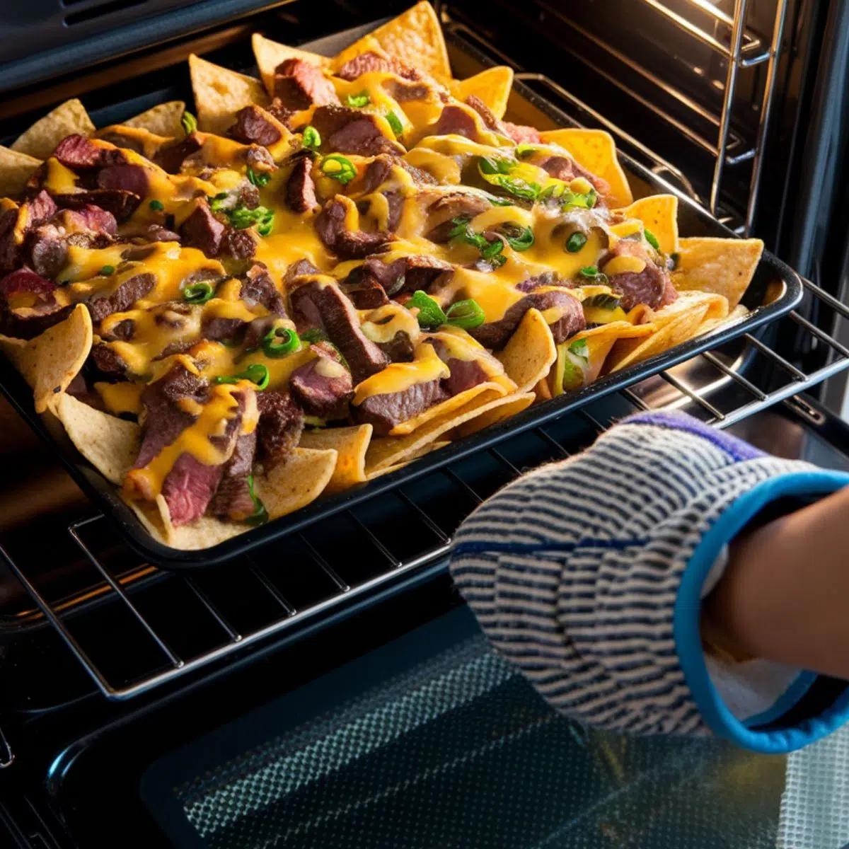  Steak nachos baking in the oven with melted cheese for steak nachos recipe.