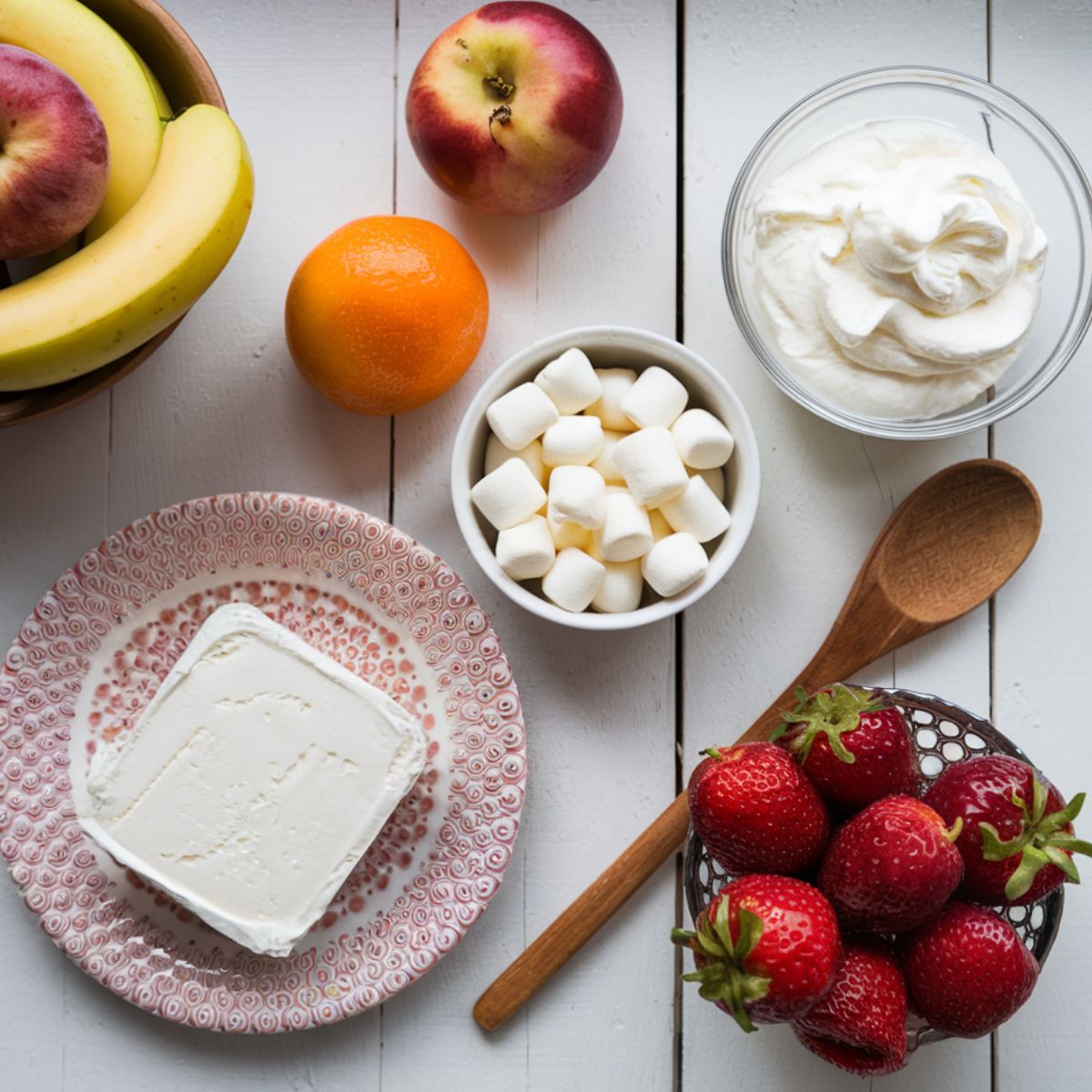 Frozen fruit salad recipe ingredients :A variety of fresh and canned fruits, cream cheese, whipped cream, and marshmallows arranged on a white kitchen counter.