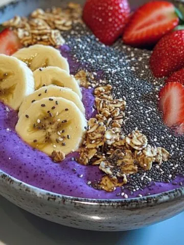 Homemade smoothie bowl recipe with colorful fruit toppings and granola on a white counter