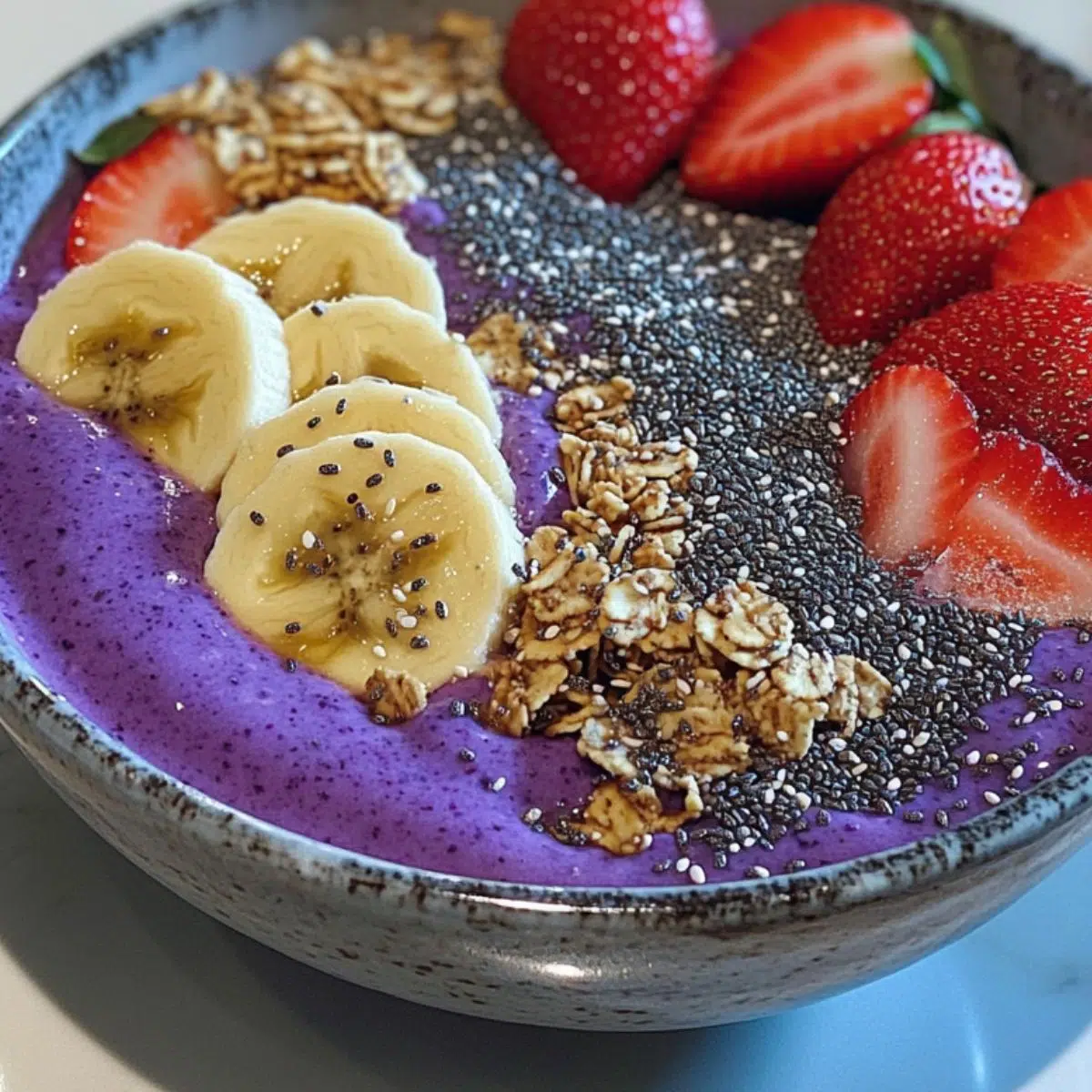 Homemade smoothie bowl recipe with colorful fruit toppings and granola on a white counter