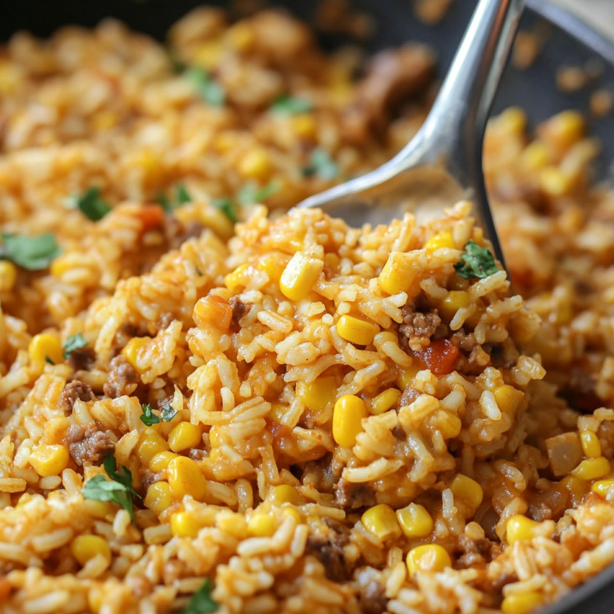 Beans, corn, and cheese being stirred into cooked taco rice