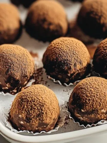 Overhead shot of homemade tiramisu truffles with cocoa topping on a white counter.