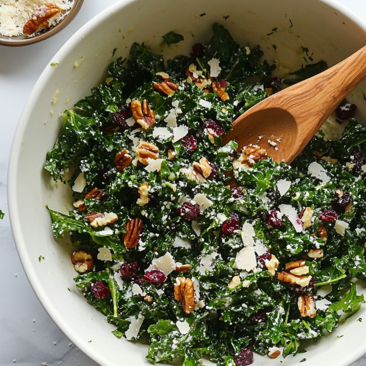 Tossing finished kale salad with pine nuts and cranberries