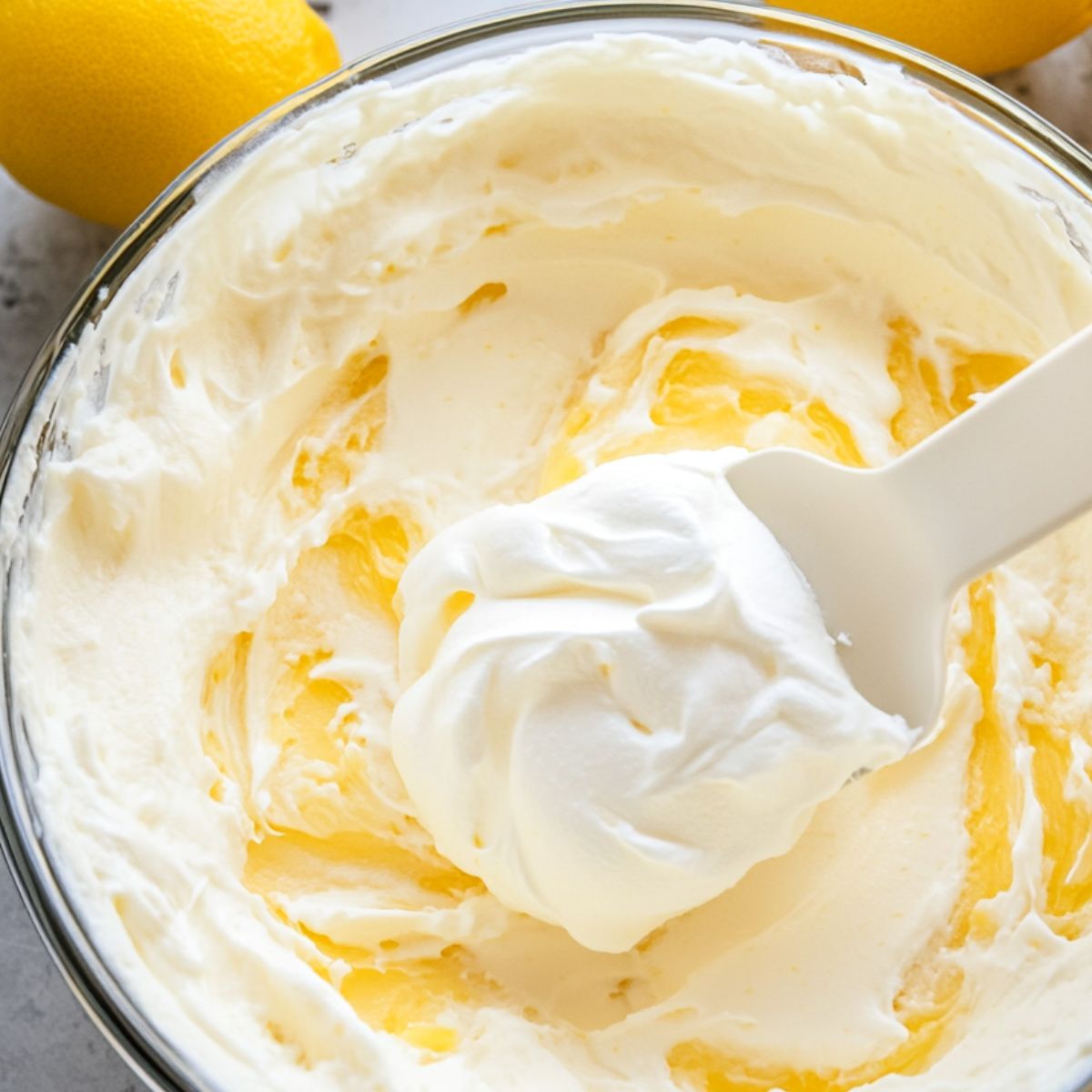 Folding whipped cream into lemon cheesecake mixture with a spatula