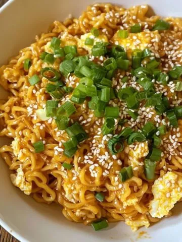 Homemade bowl of dragon noodles with spicy glaze, green onions, and sesame seeds on top