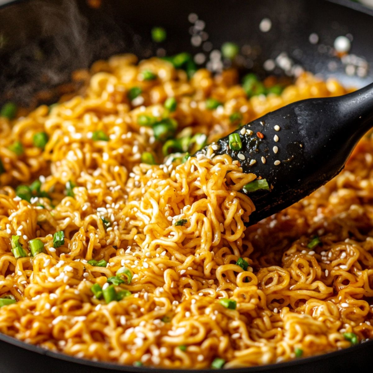 Tossing noodles in sauce with tongs in a skillet