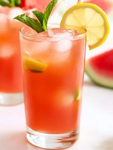 Watermelon mint lemonade in a glass with ice and mint on a kitchen counter
