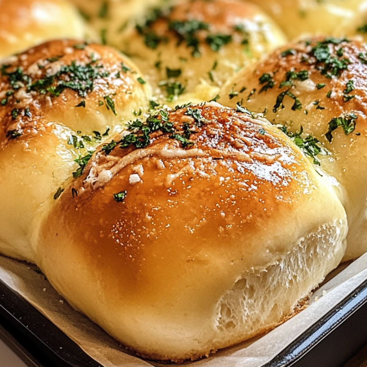Freshly baked garlic butter bread rolls brushed with garlic butter on a baking pan