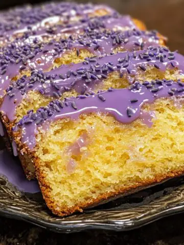 A homemade lemon lavender cake on a counter, with rustic glaze and lemon zest garnish.