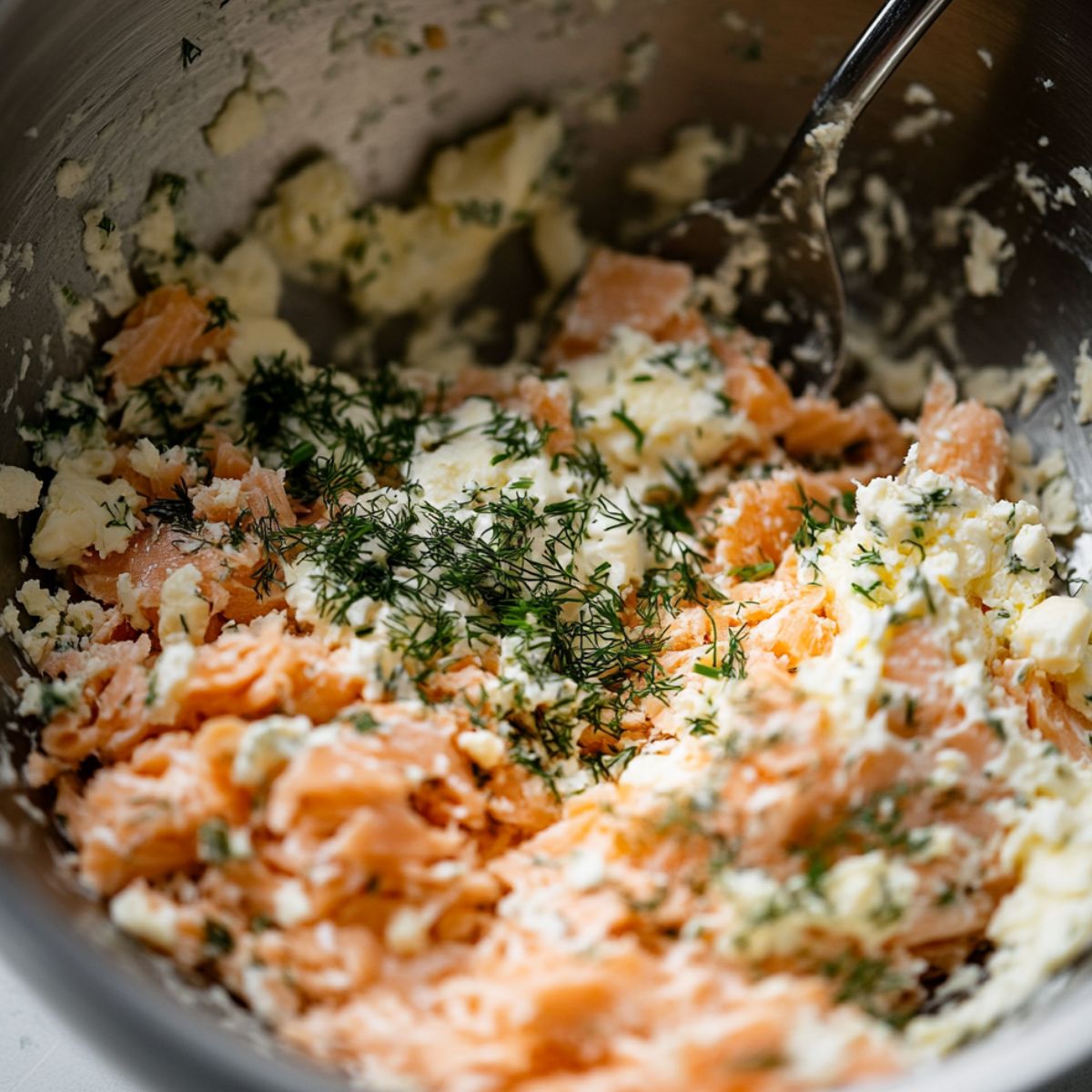 Salmon patty mixture with herbs, breadcrumbs, and mayo in a large bowl