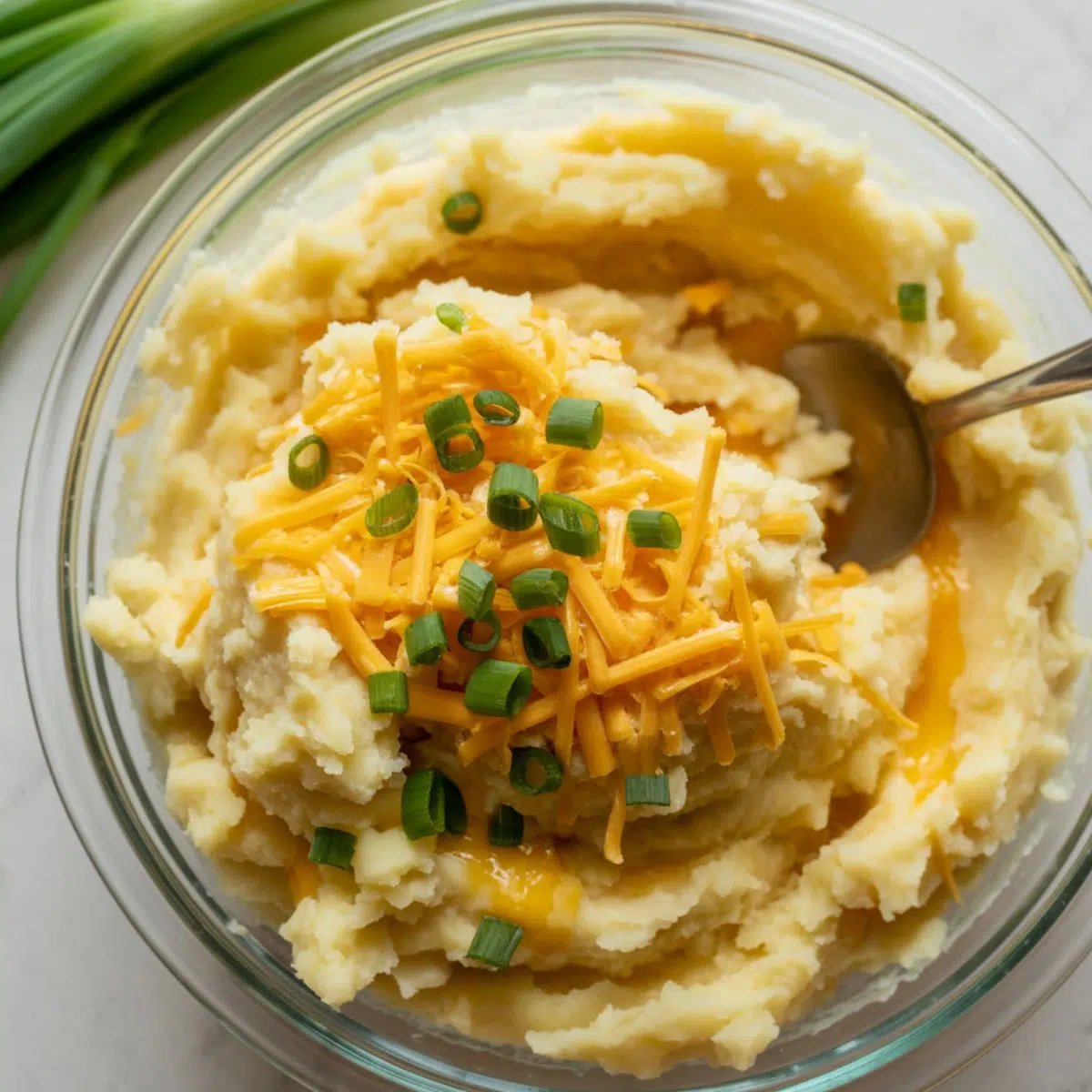 Mixing mashed potatoes with cheese and herbs in a bowl for potato cheese pancakes.