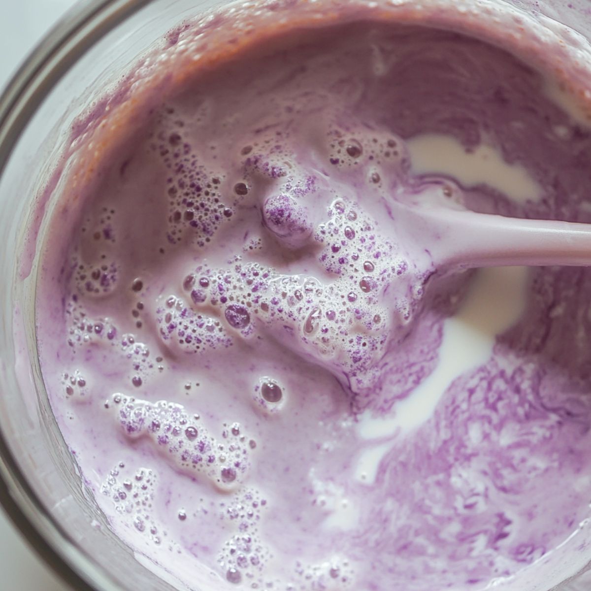 Whisking taro milk tea mixture in a bowl by hand