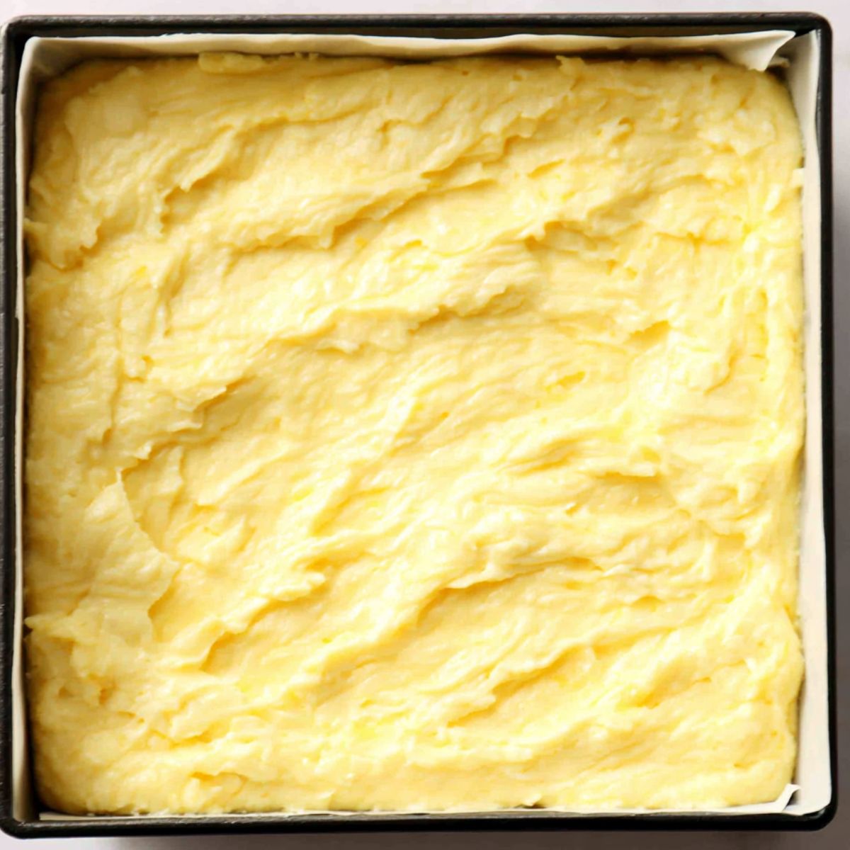 Fudgy lemon brownie batter in a pan ready to bake