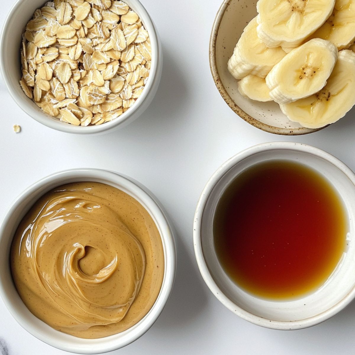 Top-down view of the four main ingredients: peanut butter, banana, oats, and maple syrup