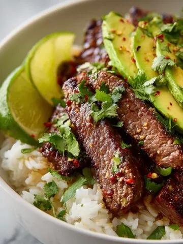 Overhead view of a homemade cilantro lime steak and rice bowl with avocado and red onions