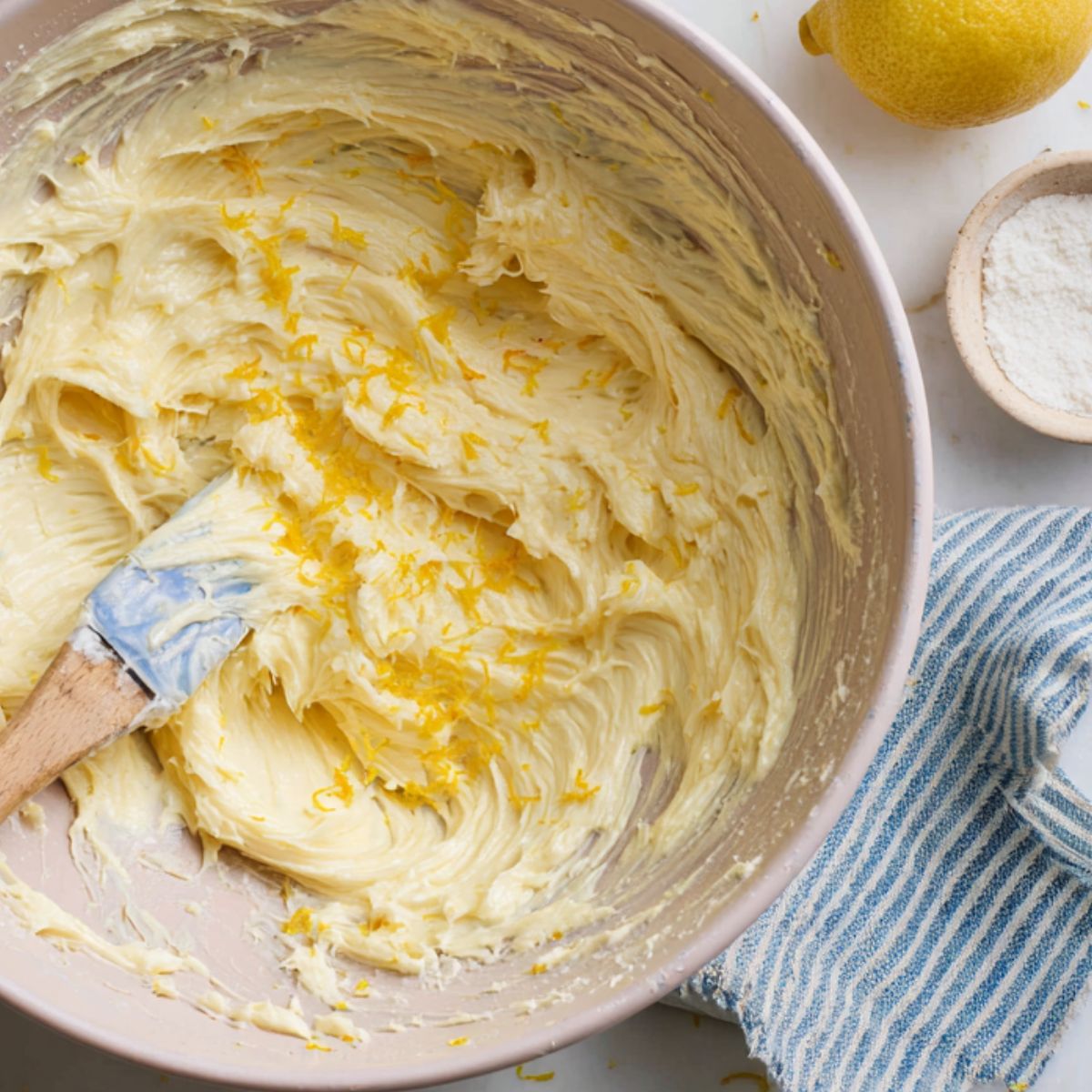 Bowl of mixed wet ingredients for lemon poppy seed cookies on a white kitchen counter