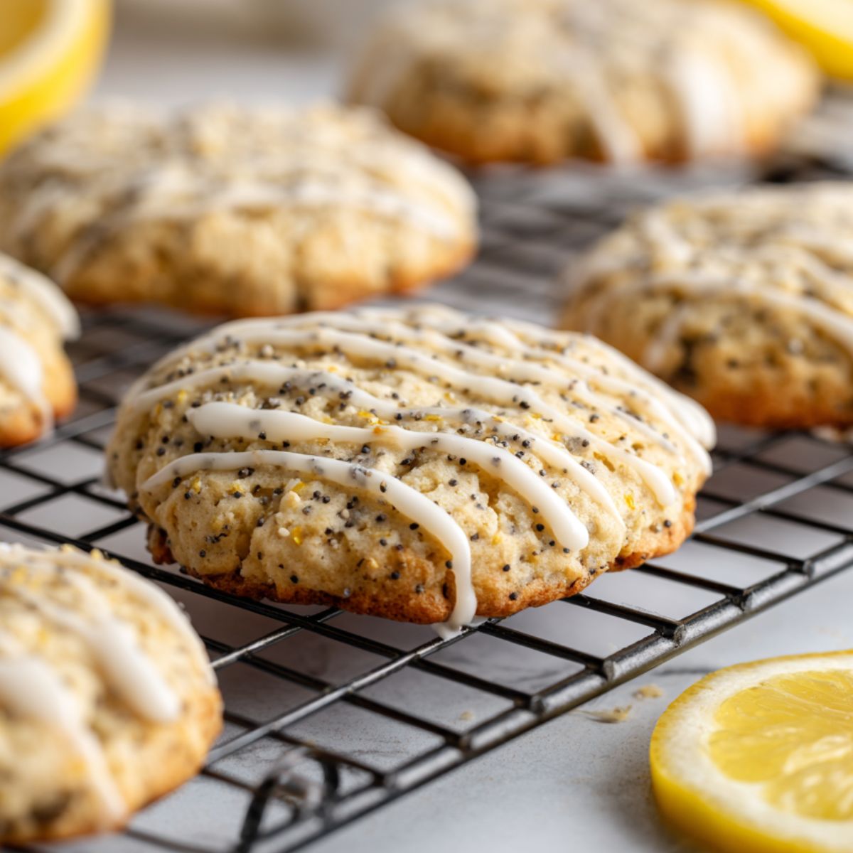 Cooling lemon poppy seed cookies being drizzled with lemon glaze on a wire rack