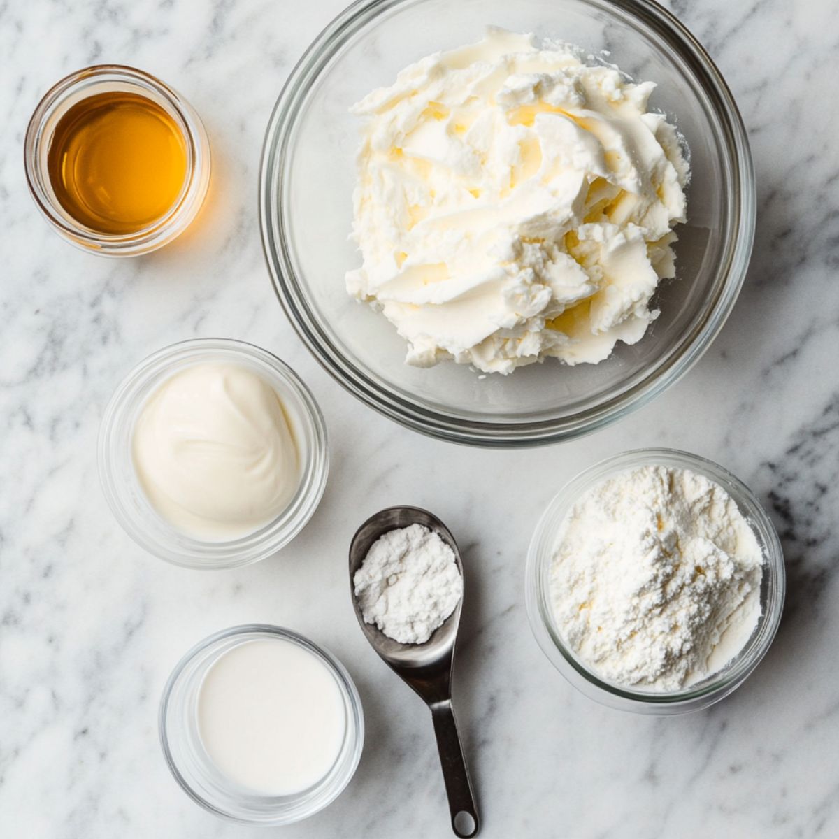 Overhead shot of ingredients for cheesecake fluff: cream cheese, Greek yogurt, protein powder, sweetener, gelatin, and vanilla on a kitchen counter.
