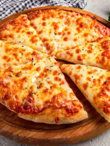 Homemade cheesy pizza with gooey cheese pull on a white kitchen counter
