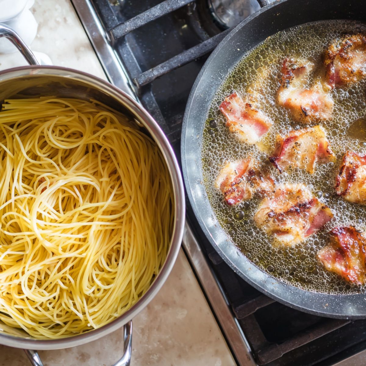 Guanciale cooking in a skillet while spaghetti boils on the stove.
