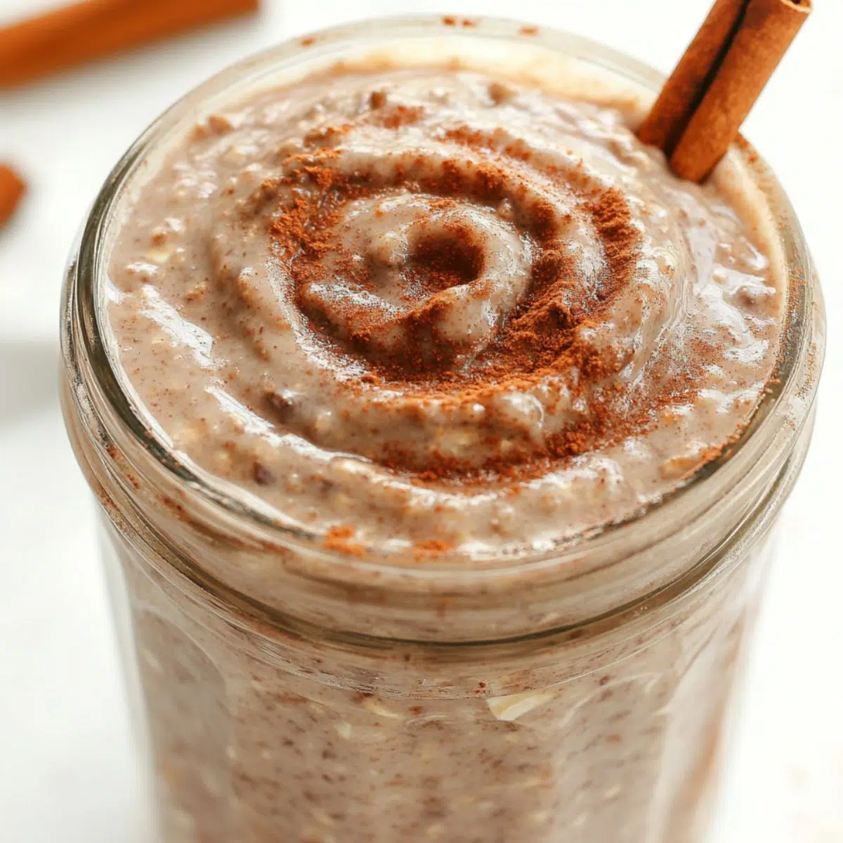 homemade jar of cinnamon roll overnight oats topped with cinnamon drizzle, sitting on a white kitchen counter