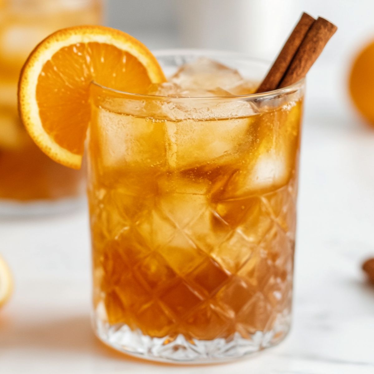 Glass of orange cinnamon iced tea with fresh orange slices and cinnamon sticks