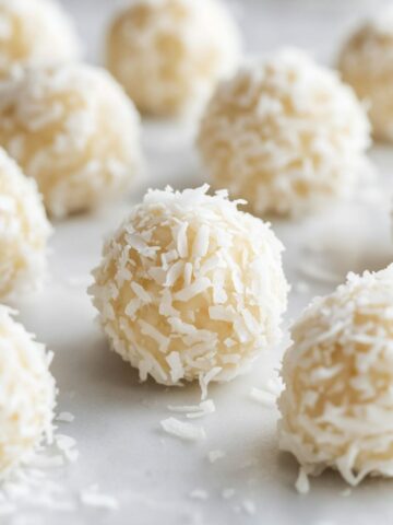 Homemade coconut balls rolled in coconut, on a white counter