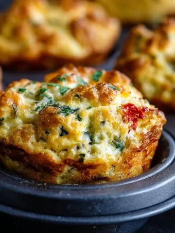 Freshly baked cottage cheese egg muffins cooling on a muffin tray on a white kitchen counter.