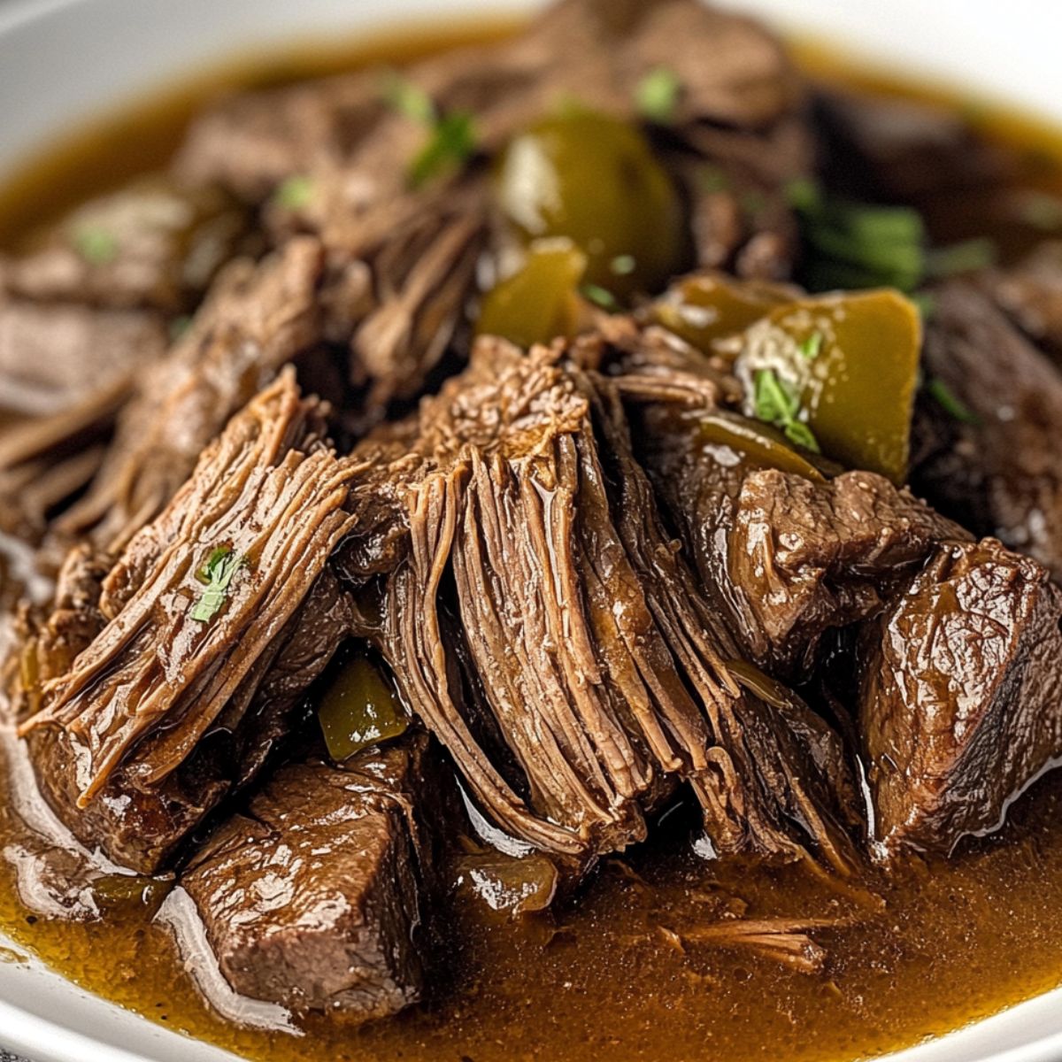 Mississippi roast Instant Pot served with gravy and pepperoncini on a white plate