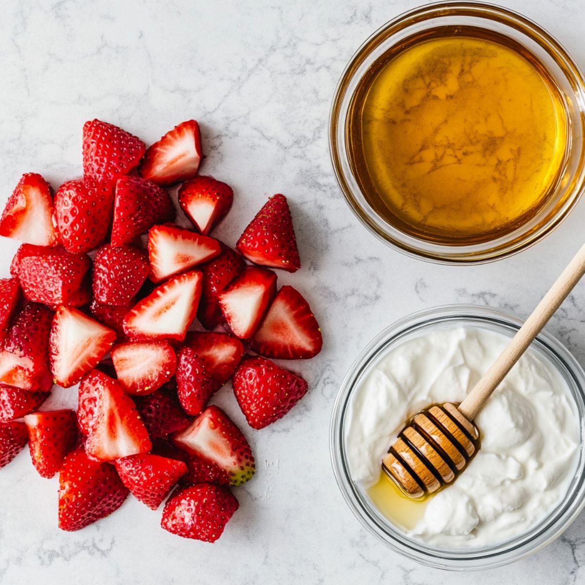 Fresh strawberries, yogurt, and honey on a white kitchen counter ready for frozen yogurt bites