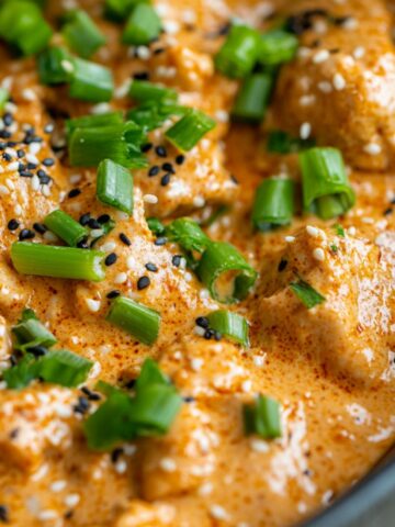 keto bang bang chicken in a bowl with sauce and garnishes, homemade style