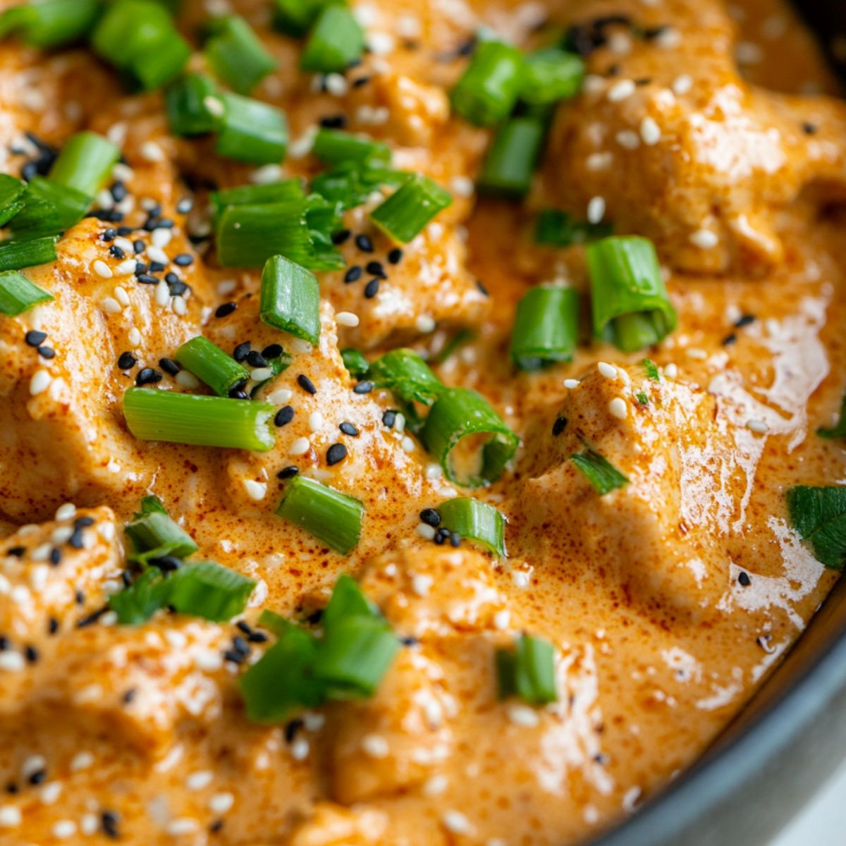  keto bang bang chicken in a bowl with sauce and garnishes, homemade style