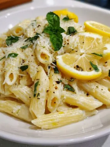 Overhead shot of lemon basil ricotta pasta served in a white bowl on a home kitchen counter