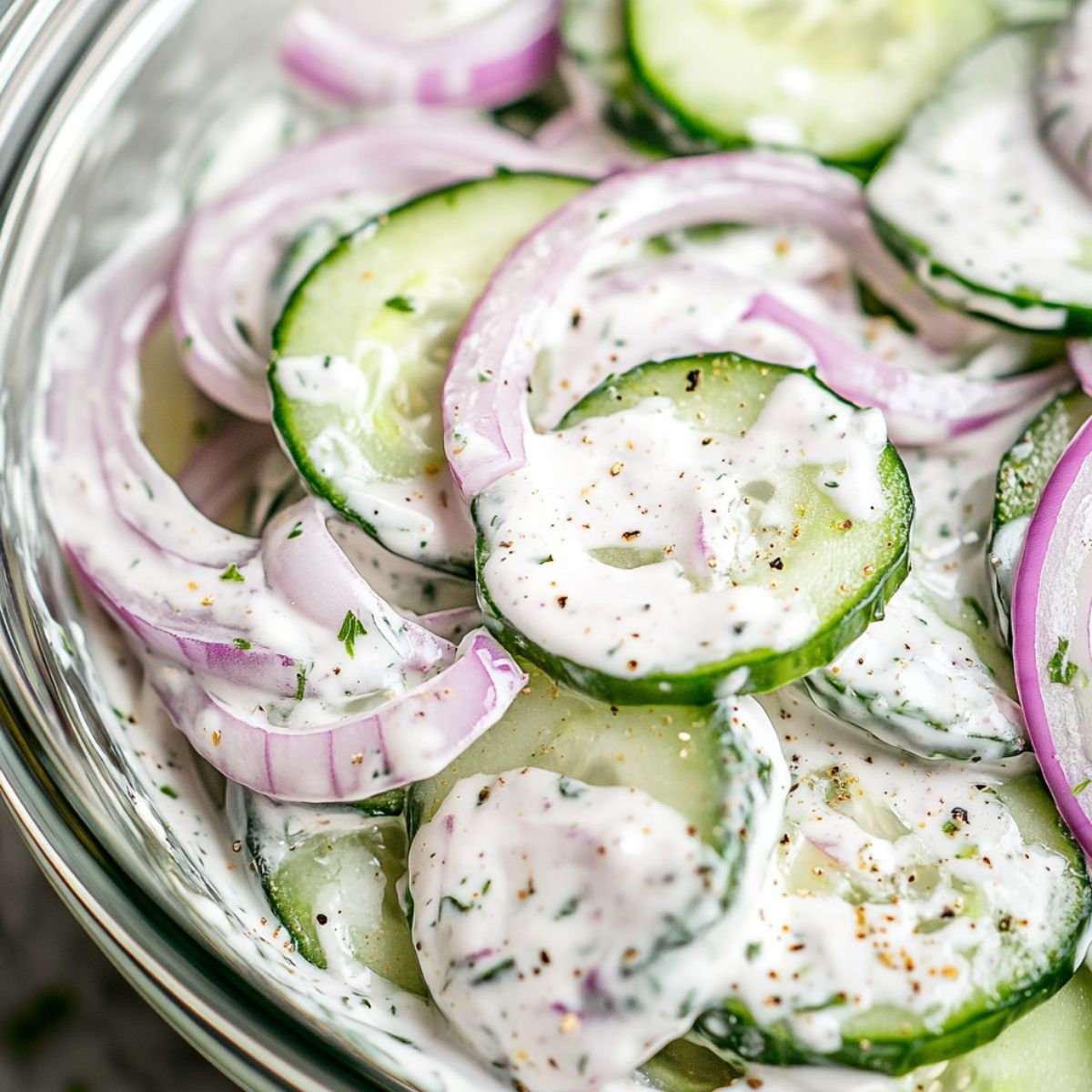  Mixing cucumbers and onions into creamy dressing in a large bowl