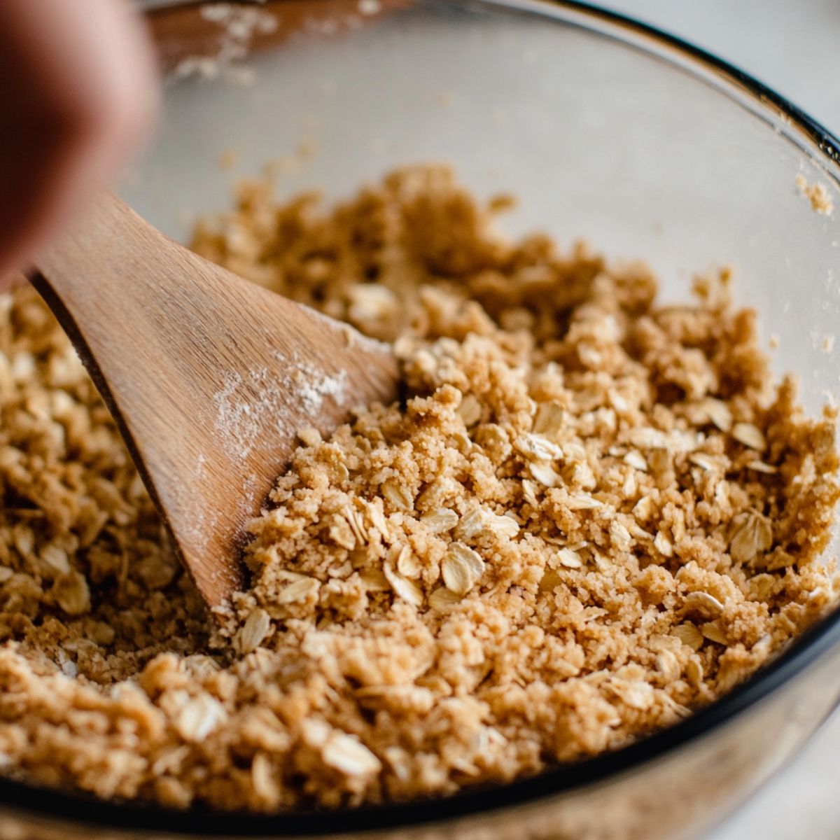Mixing the oat topping for breakfast apple crumble by hand