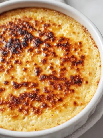 Oatmeal custard baking in a dish with golden edges on a white kitchen counter.
