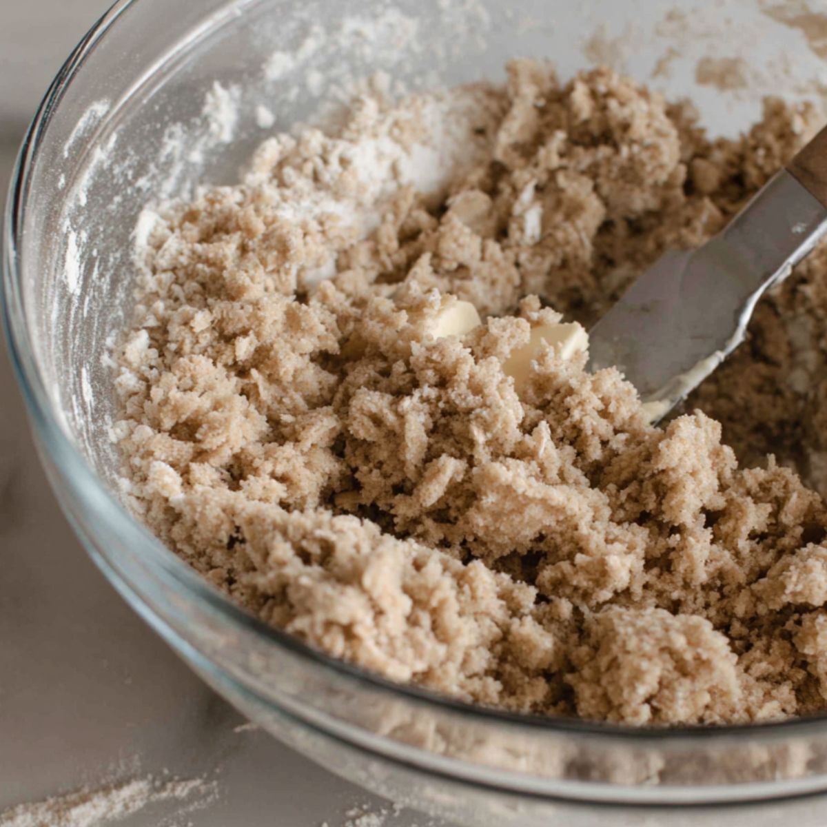 Butter being cut into the oat crumble mixture with fingertips in a large mixing bowl