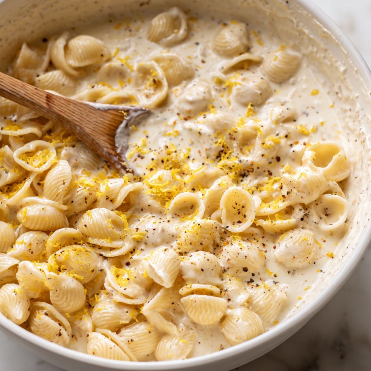 Stirring pasta with the creamy lemon feta sauce