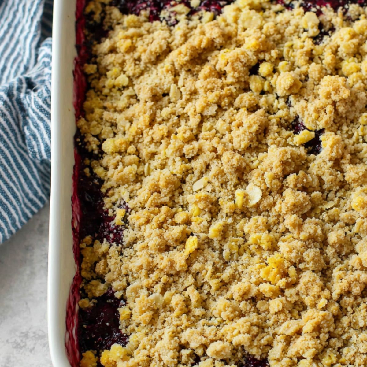 Unbaked berry crisp in a dish with crumble topping scattered over the berry filling