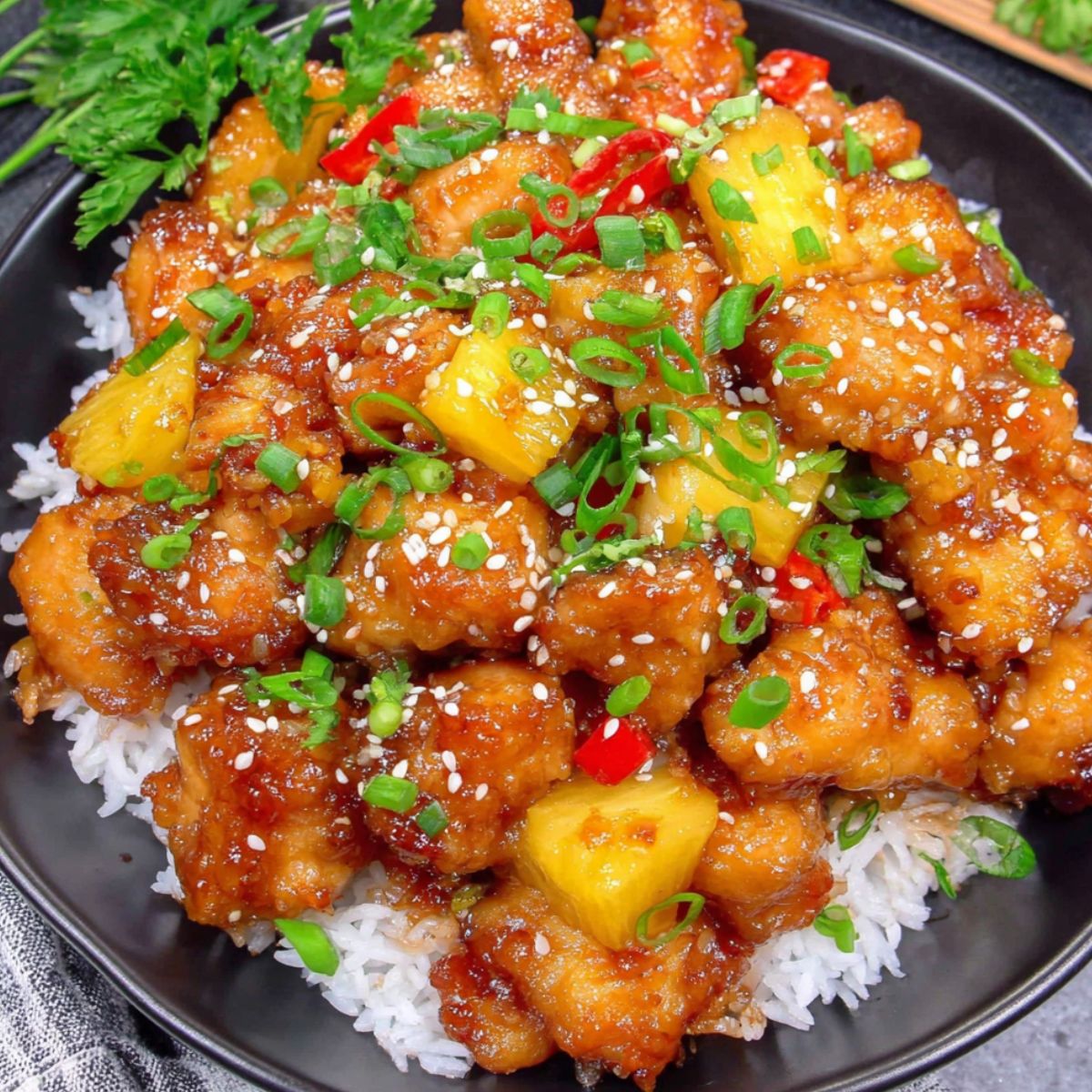 A plate of Sweet Hawaiian Crockpot Chicken over rice with pineapple and bell peppers.