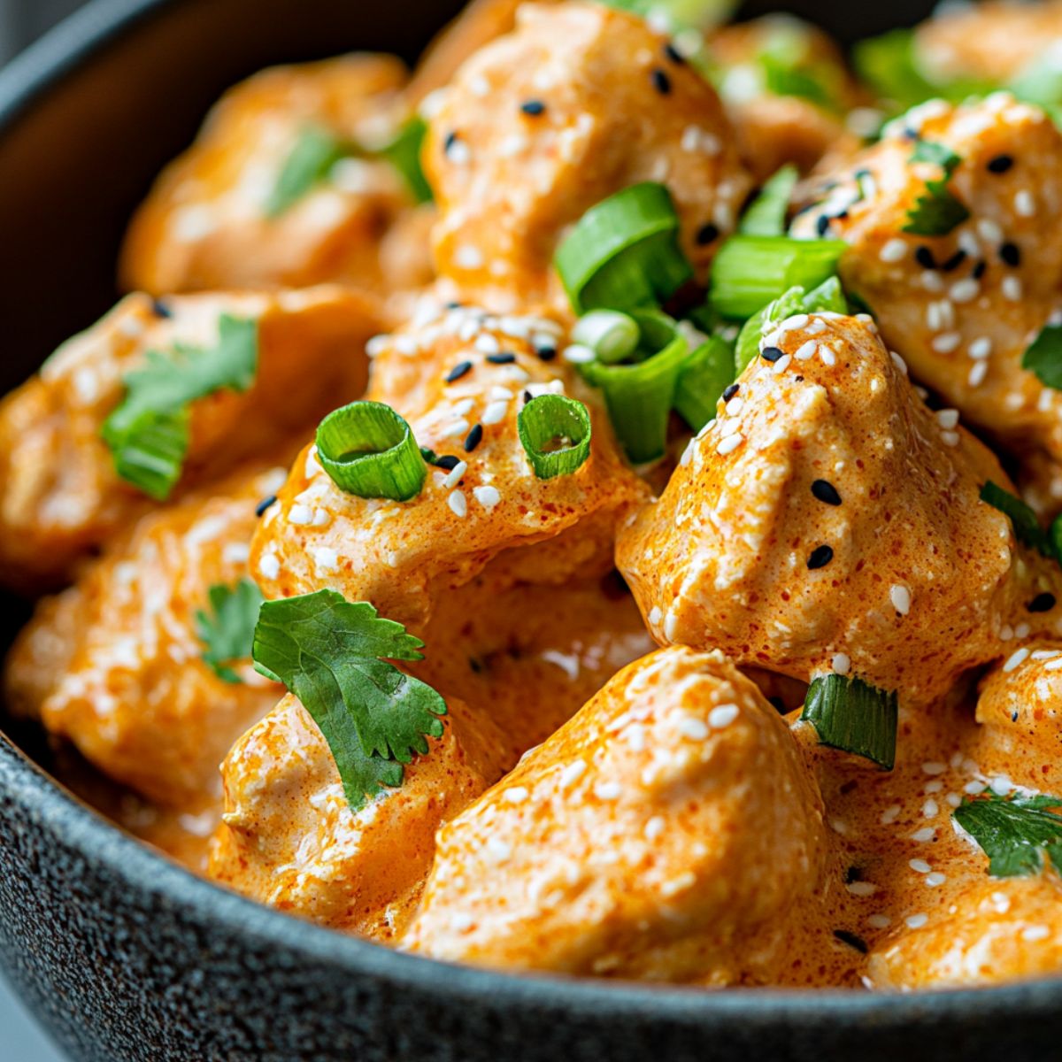 Keto chicken tossed in bang bang sauce with garnishes