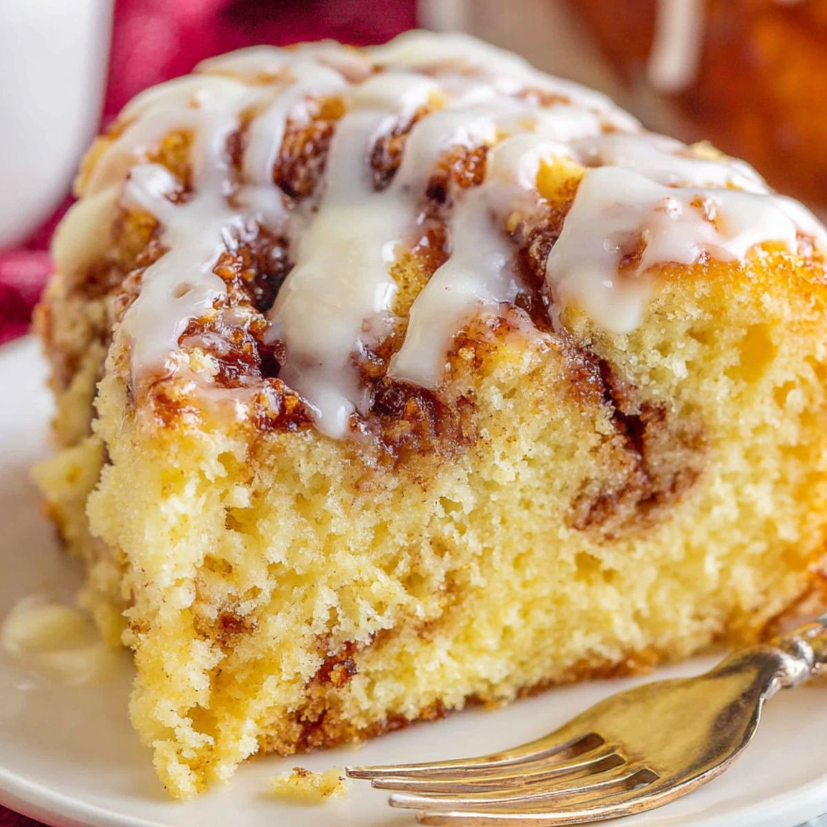 A slice of Cinnamon roll cake mix with icing drizzle on a white plate