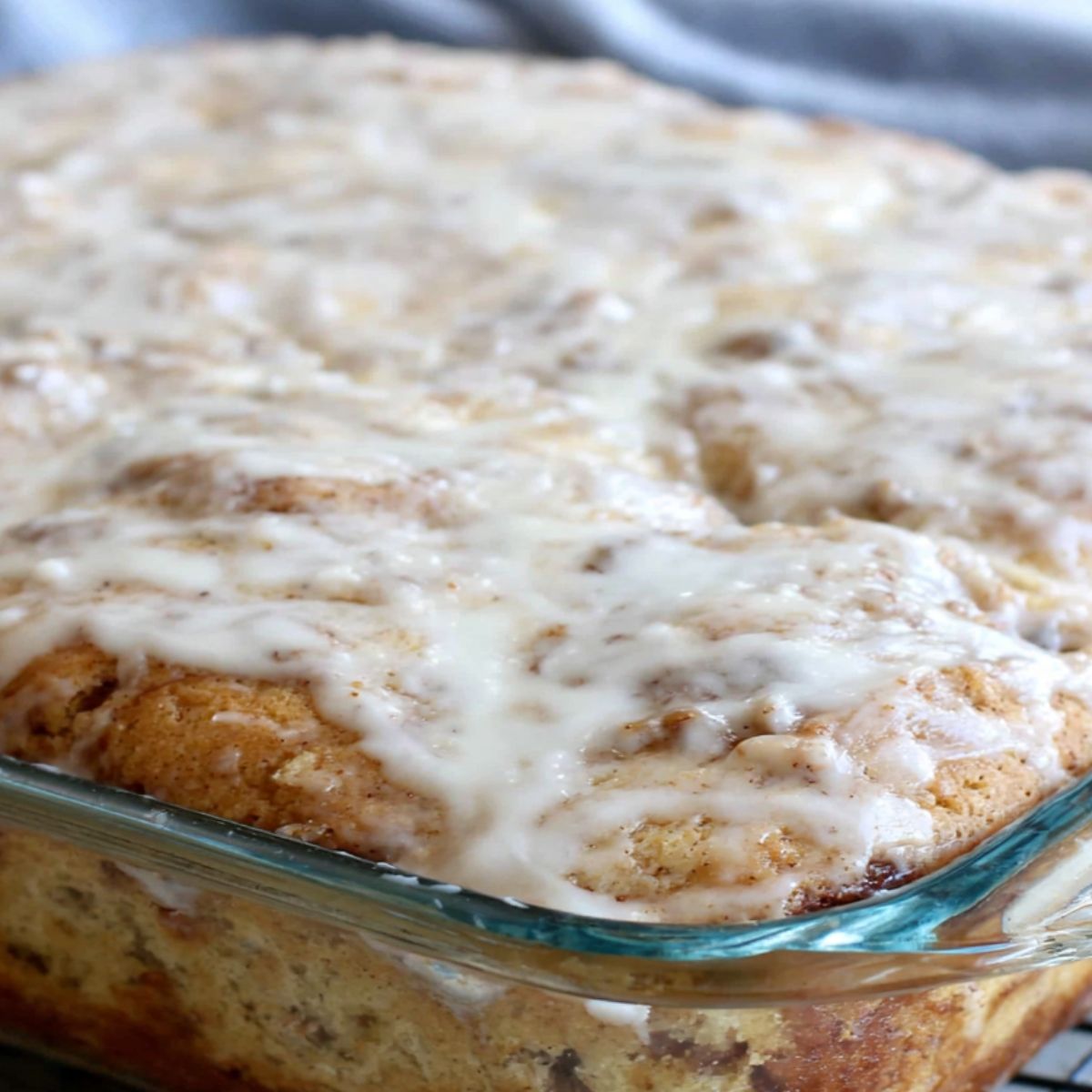Drizzling glaze over warm cinnamon roll cake