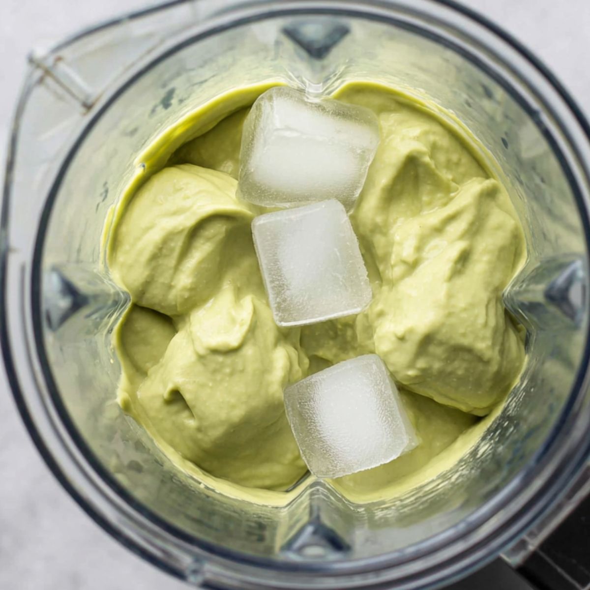 Adding ice to the blended avocado smoothie