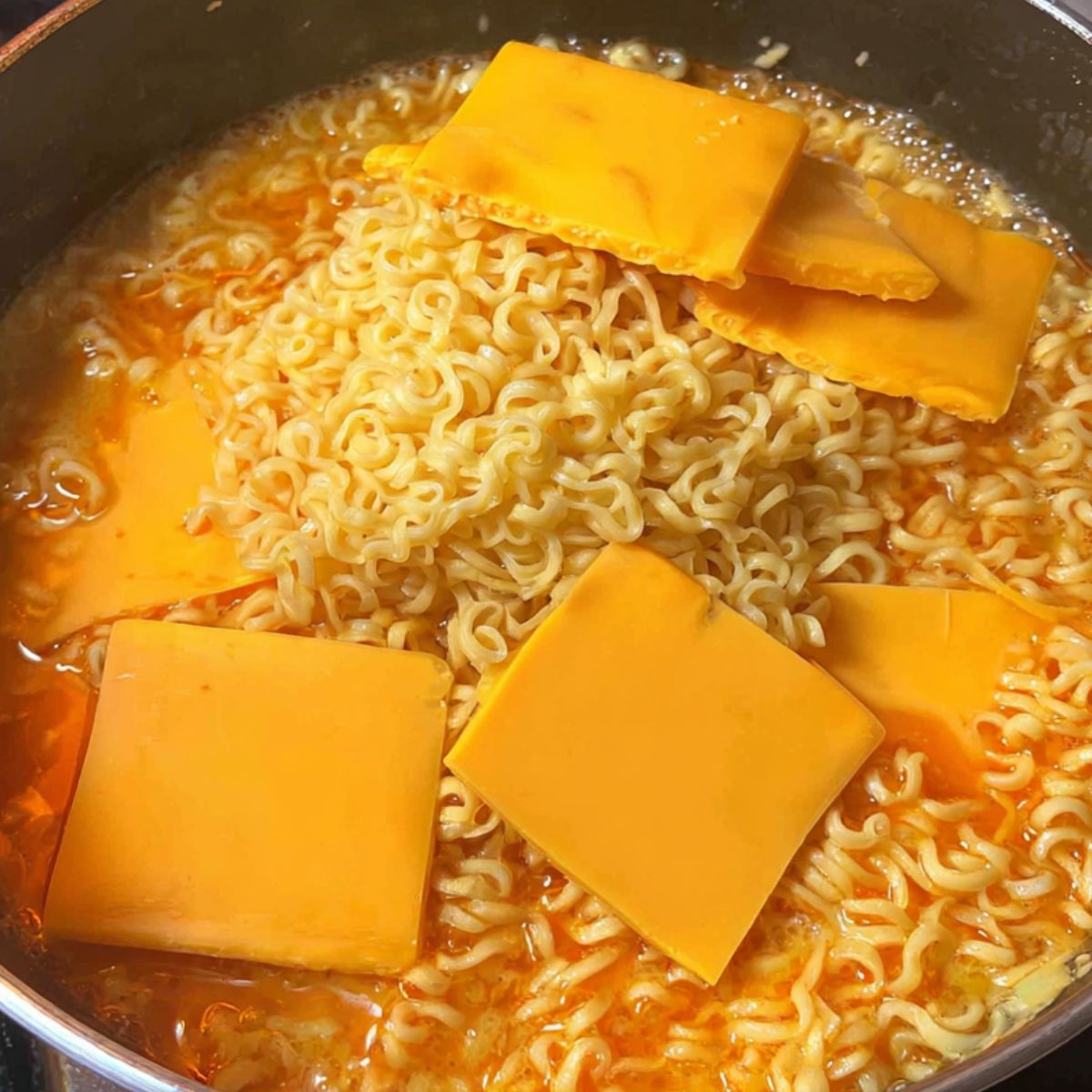 Cheese melting into hot ramen broth in a pot.